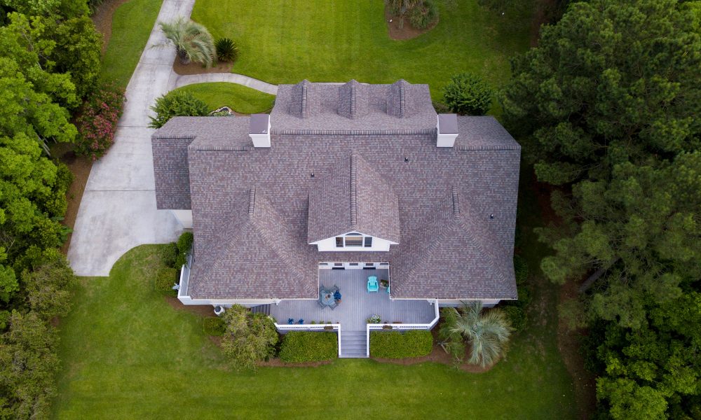 Aerial view of large home with new roof on beautiful property.